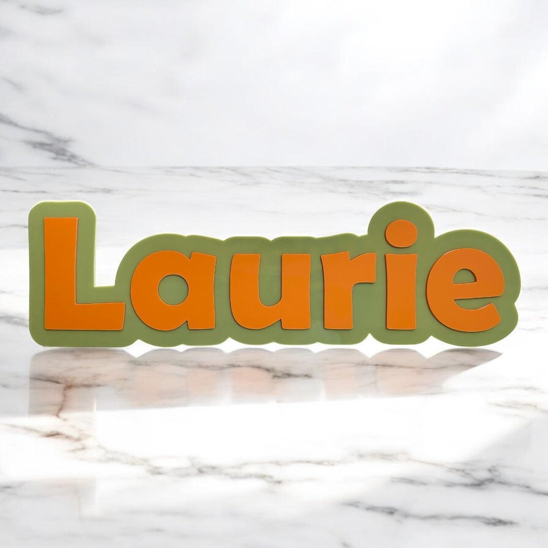 Name 'Laurie' in orange letters on a green border against a marble background