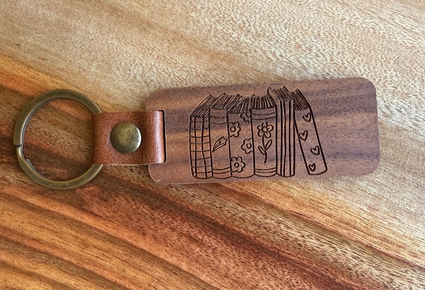 Wooden keychain with leather strap and engraved design on a wooden surface
