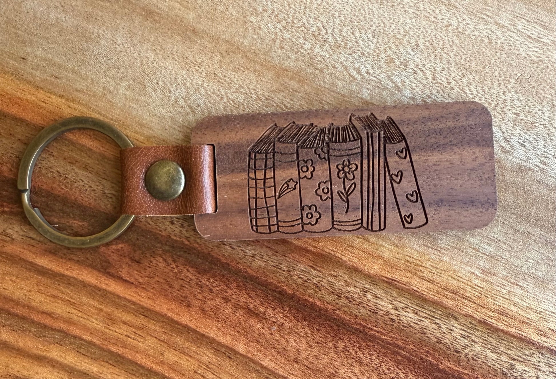 Wooden keychain with leather strap and engraved design on a wooden surface