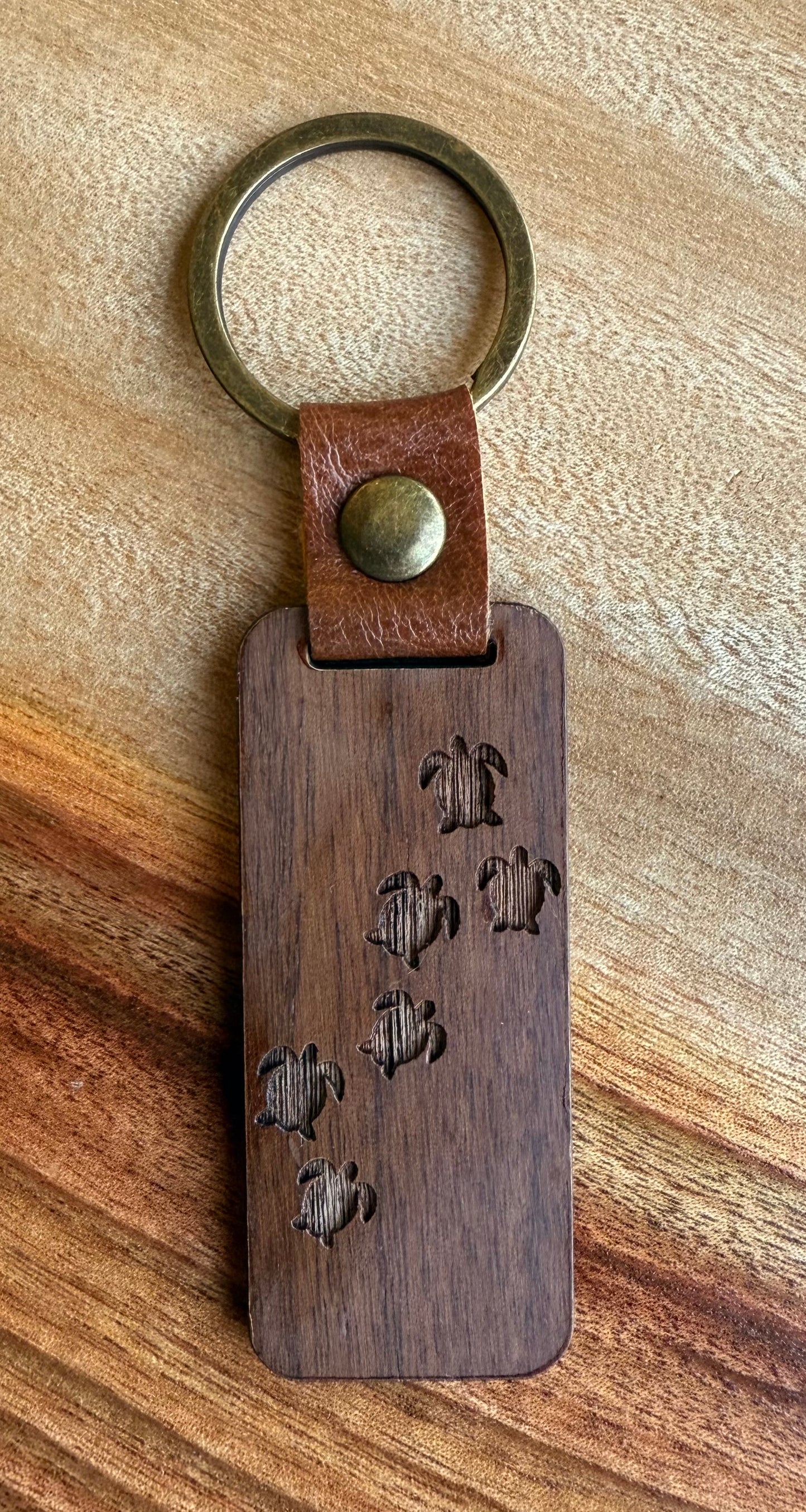 Wooden keychain with leather strap and engraved design on a wooden surface