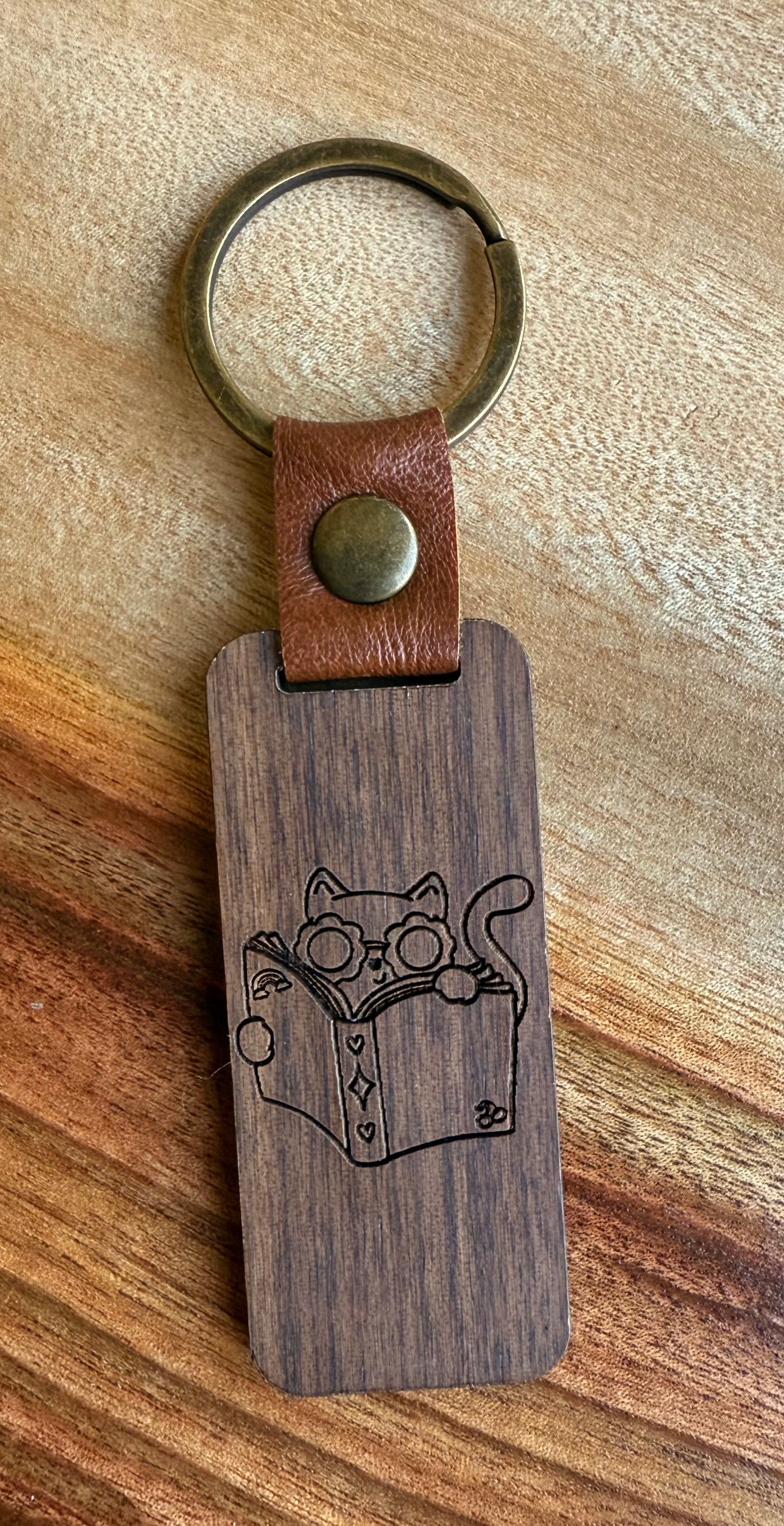 Wooden keychain with leather strap and engraved design on a wooden surface