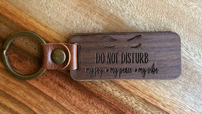 Wooden keychain with engraved text on a wooden surface