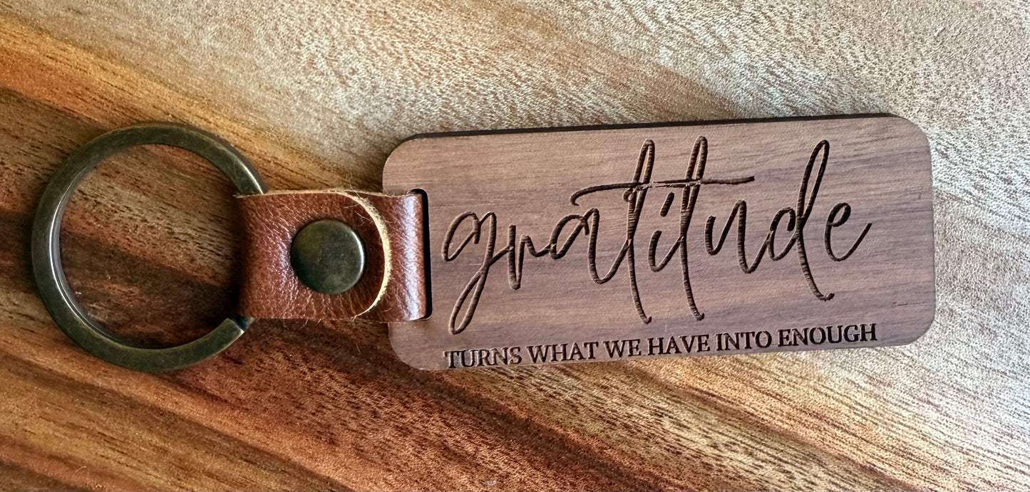 Wooden keychain with 'gratitude' engraving on a wooden surface