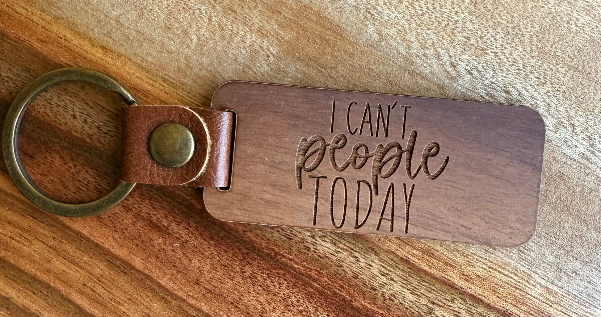 Wooden keychain with 'I can't people today' text on a wooden surface