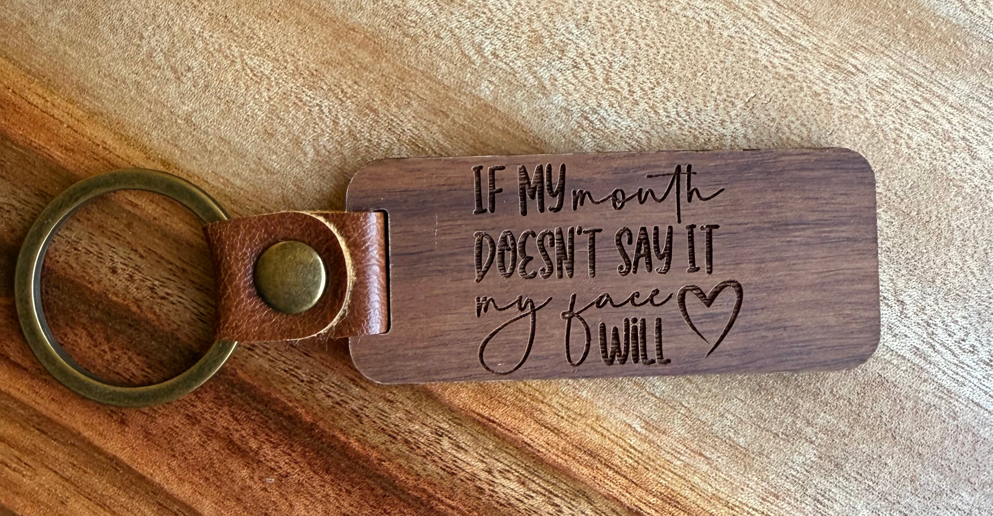 Wooden keychain with engraved text on a wooden surface
