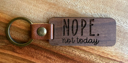 Wooden keychain with leather strap and 'NOPE. not today' text on a wooden surface
