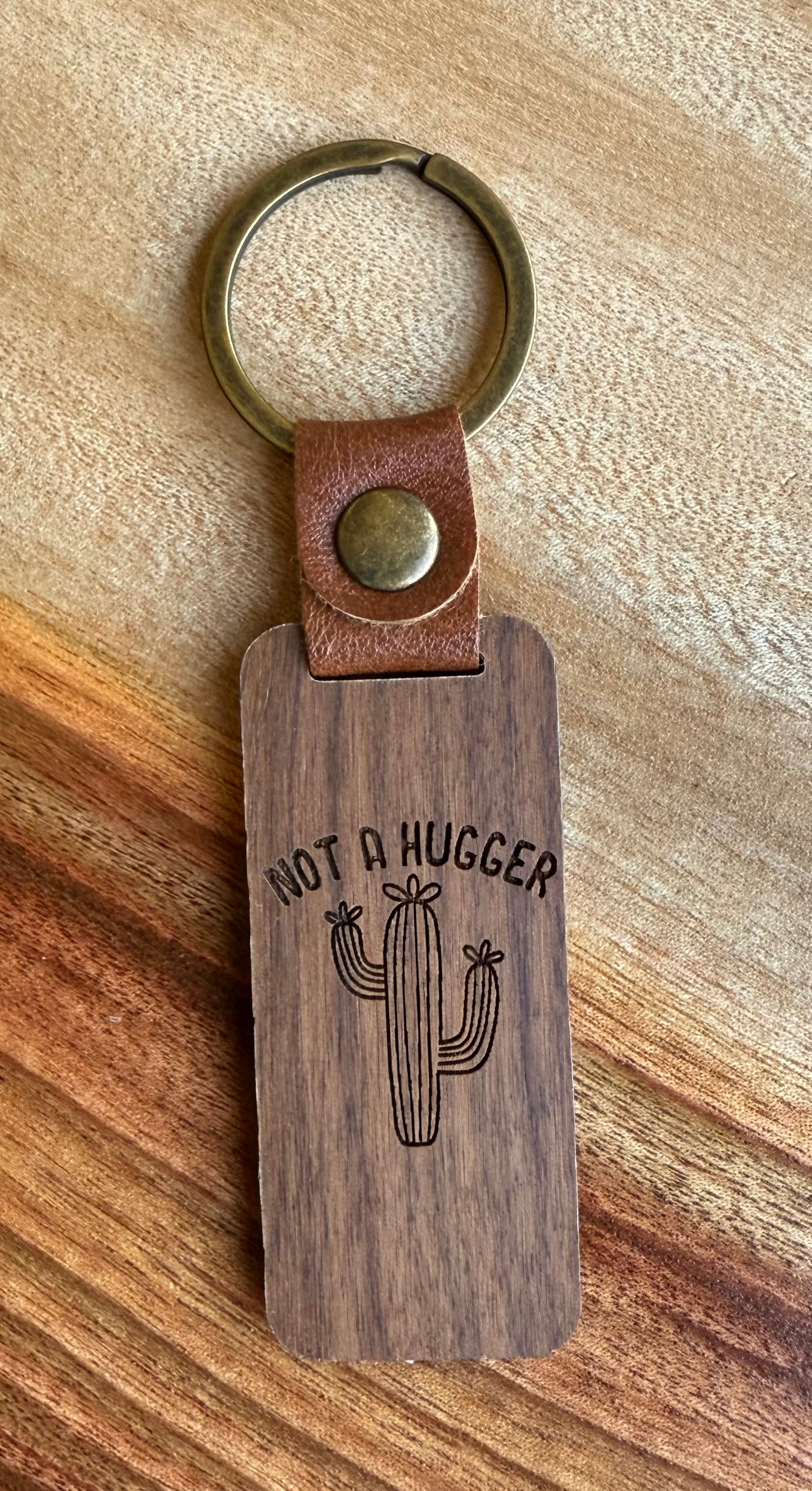 Wooden keychain with leather strap and cactus design on a wooden surface