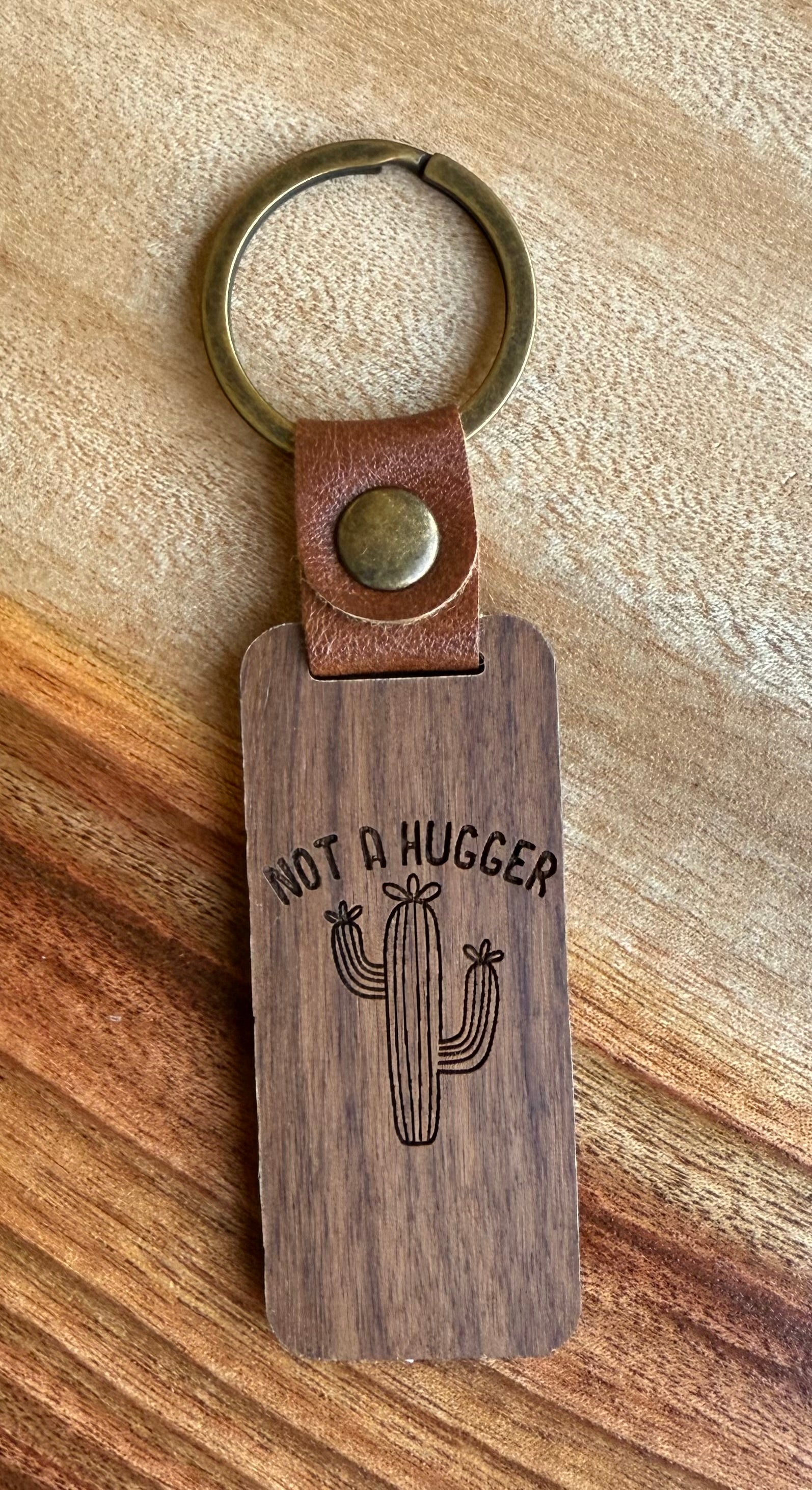 Wooden keychain with leather strap and cactus design on a wooden surface