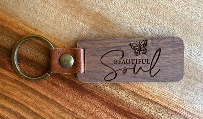 Wooden keychain with leather strap and 'Beautiful Soul' engraving on a wooden surface
