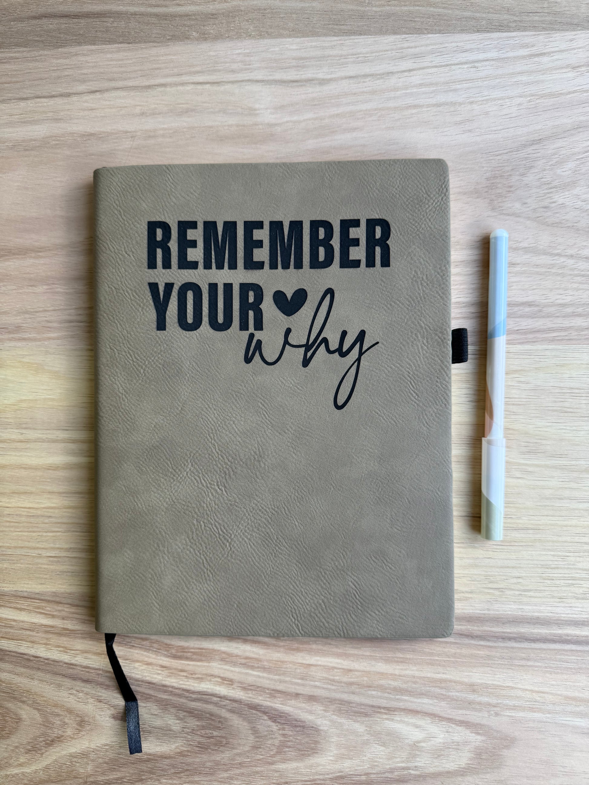 Notebook with 'Remember Your Why' text on a wooden surface