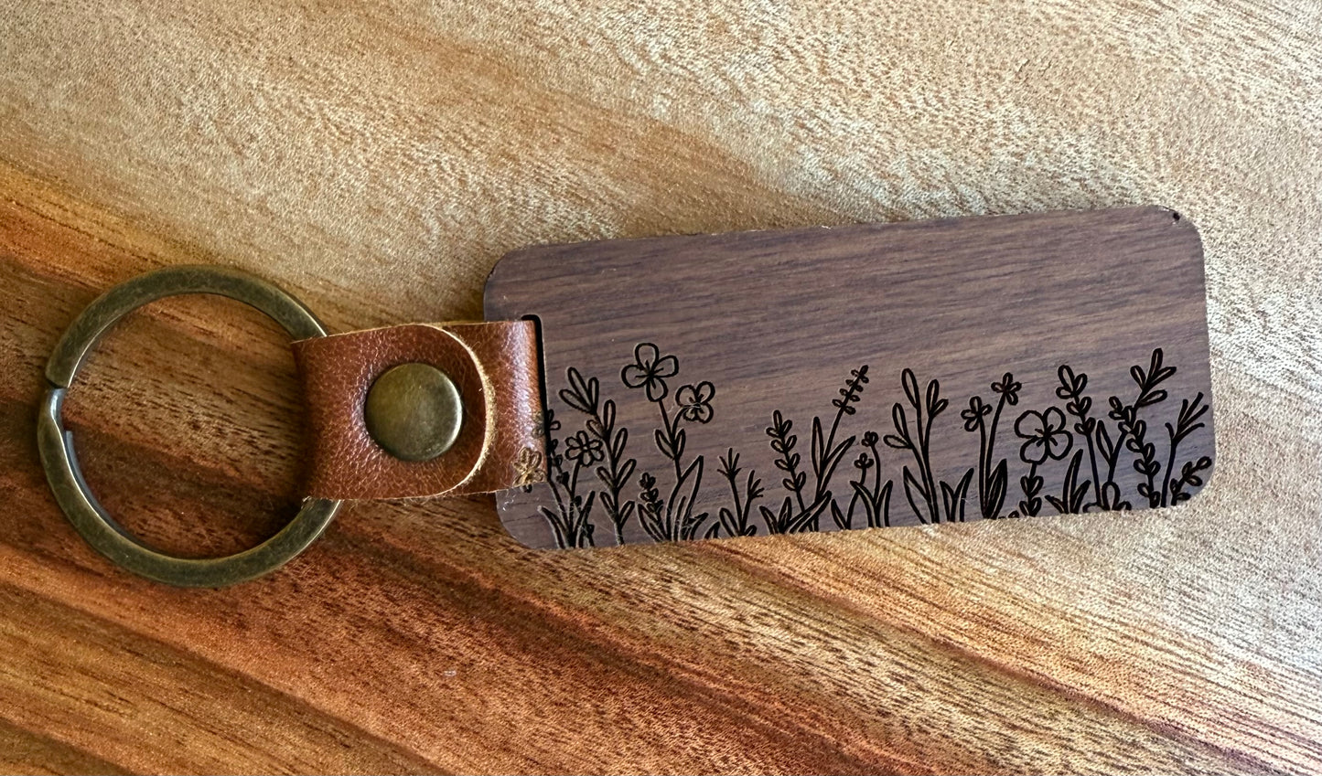 Wooden keychain with floral engraving on a wooden surface