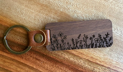 Wooden keychain with floral engraving on a wooden surface